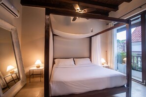 Una cama con dosel con ropa blanca, un espejo grande y dos lámparas de noche.