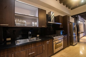 A modern kitchen with dark wood cabinets, stainless steel appliances, and a black countertop. - Luxury 7 Bedroom Villa in Walled City (Cartagena de Indias)