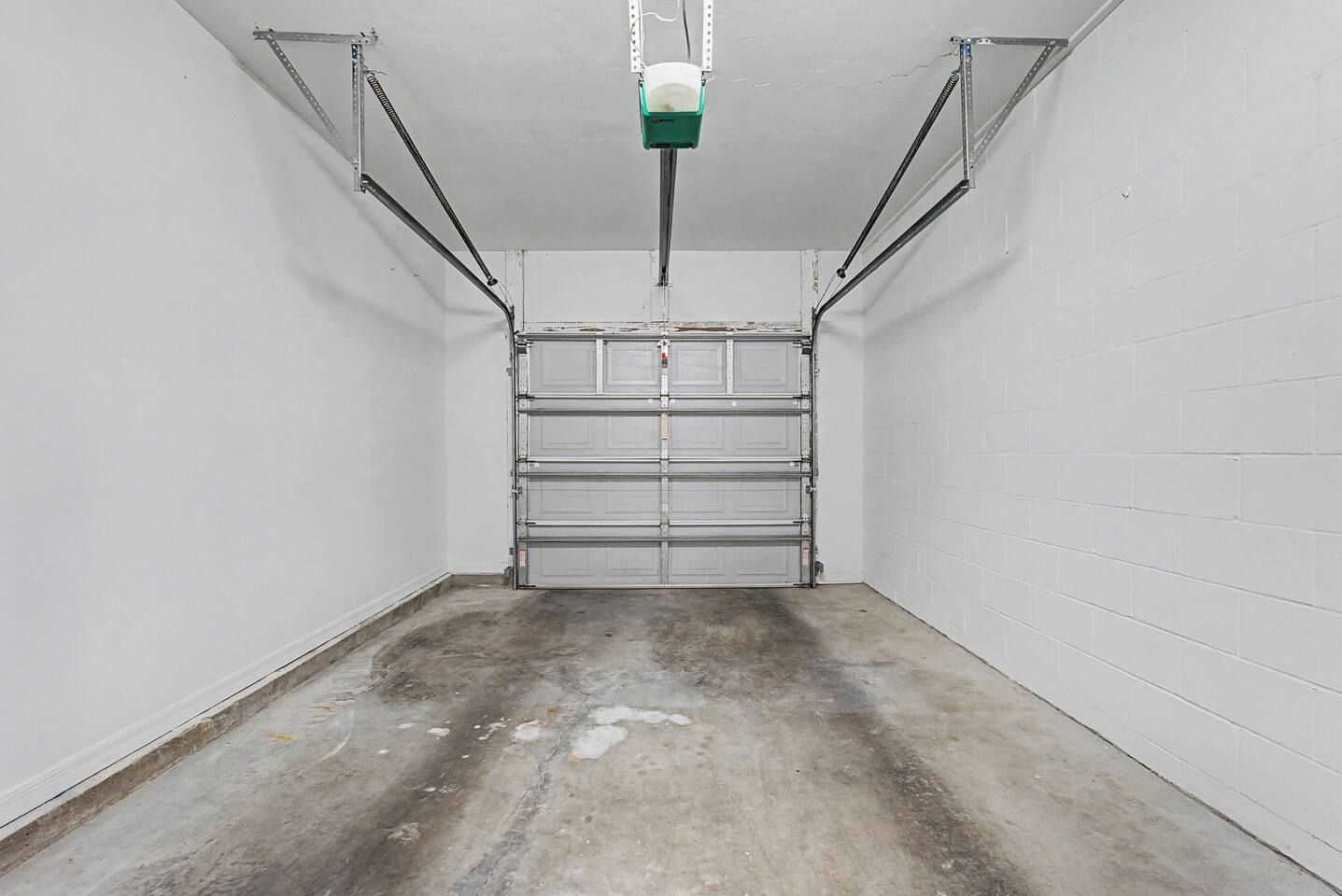 Un garage propre et vide, avec des murs blancs et un sol en béton.