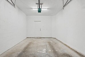 A room with white brick walls, a concrete floor, a door, and a ceiling light fixture. - Cozy Gainesville Apt • 2BR 2BA Stay near UF Campus (Gainesville)