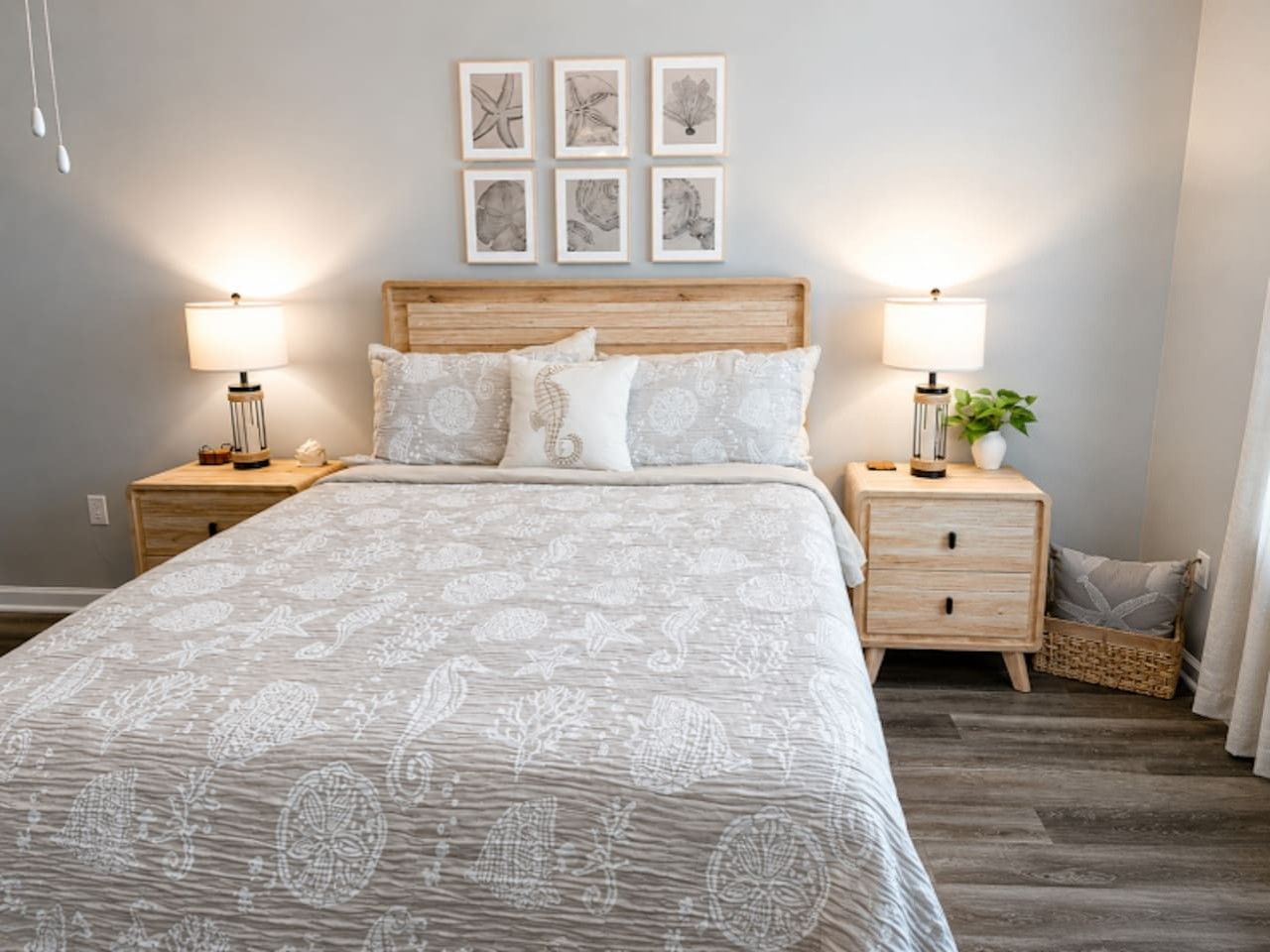A bedroom with a bed, two bedside tables, a headboard, and framed artwork on the wall.