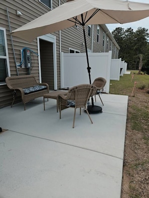Un patio al aire libre con mobiliario de mimbre y una sombrilla grande.