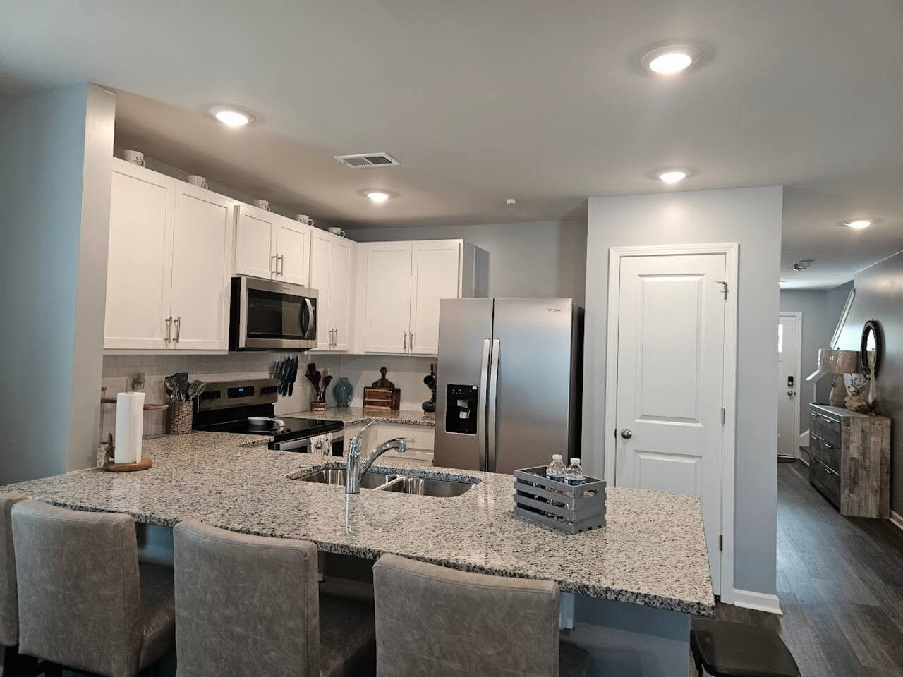 A modern kitchen with granite countertops, stainless steel appliances, and a central island with bar seating.