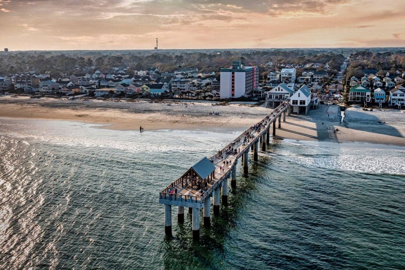 Un muelle que se adentra en el agua, con un pueblo al fondo.