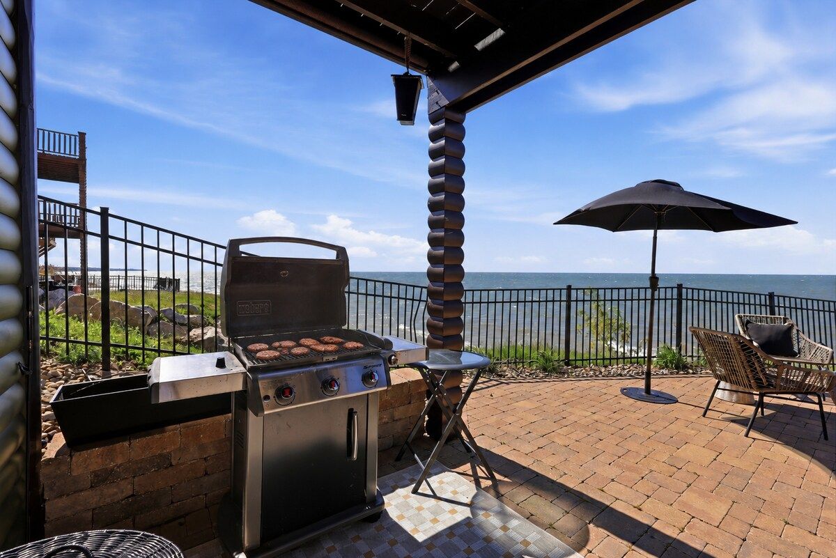 An outdoor patio with a grill, a folding chair, and an umbrella.
