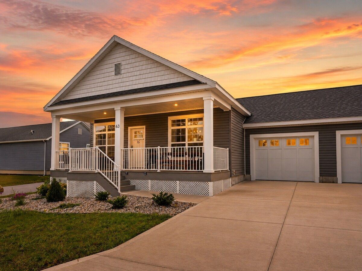 A residential house with a covered porch, a garage, and a well-maintained lawn.