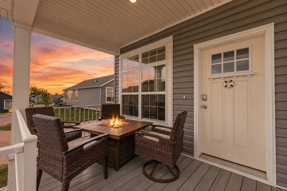 A covered patio with a table and chairs, a fire feature, and a door with a window and a lifebuoy.