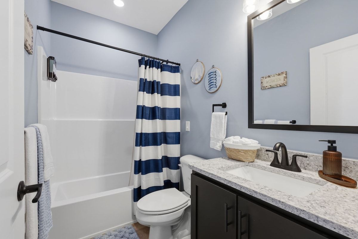 A bathroom with a bathtub, a toilet, a sink with a mirror, and a shower curtain.