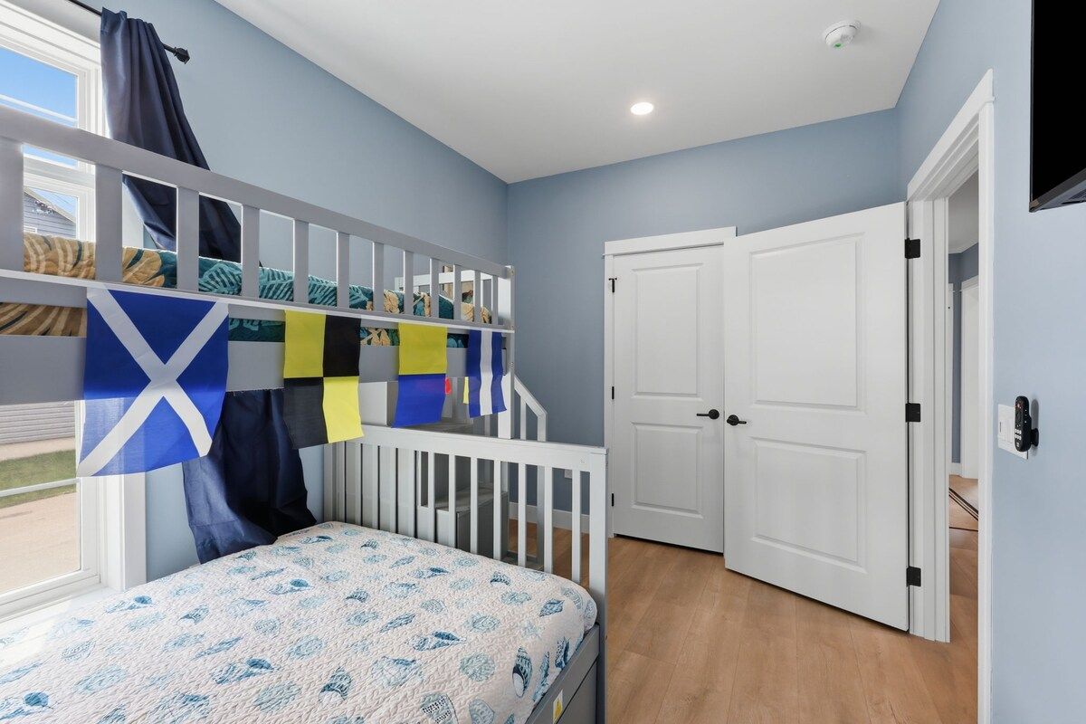 A room with a bunk bed, a door, and a window.