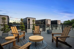 A rooftop deck with wooden furniture, potted plants, and a clear view of the city skyline. - Twin Terraces-Skyline Views with Two Rooftop Decks (Cleveland)