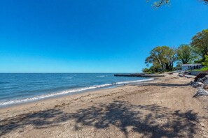 Ein Strand mit blauem Himmel, ruhiger See und felsiger Küste.