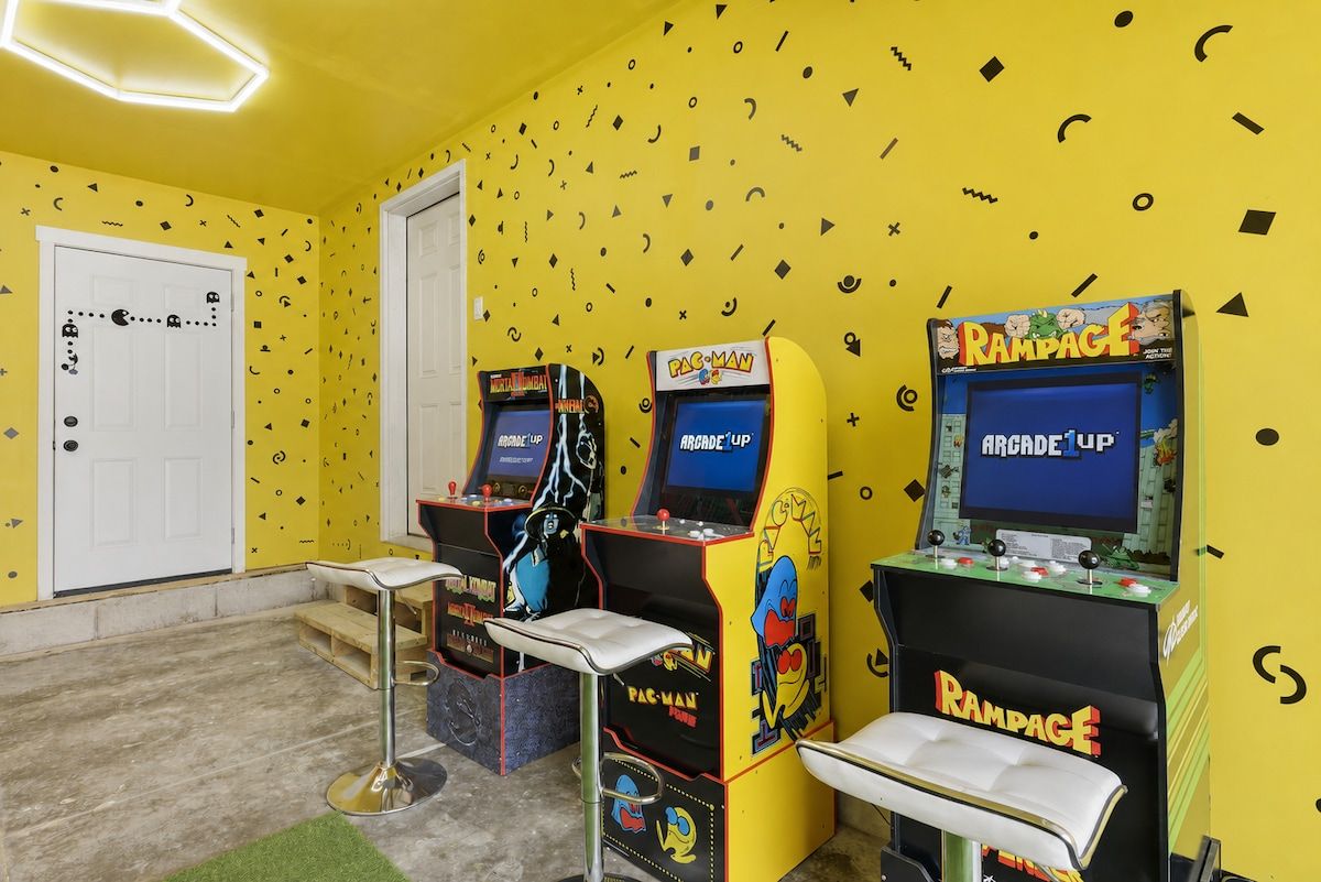 Ein Raum mit Spielautomaten, einer Tür und einer kleinen Sitzecke.