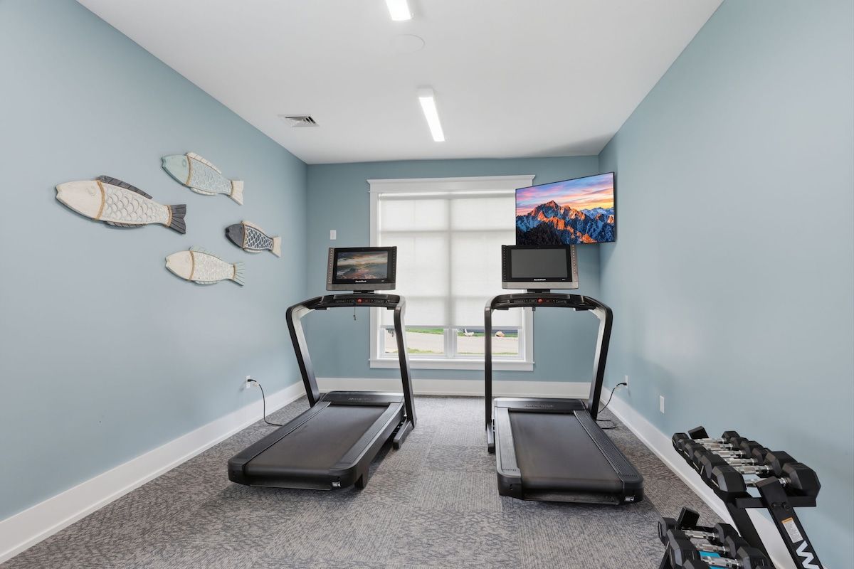 A room with two treadmills, a TV, and dumbbells.