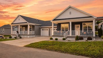 A residential area with two houses, each featuring a front porch, a garage, and a well-maintained lawn.