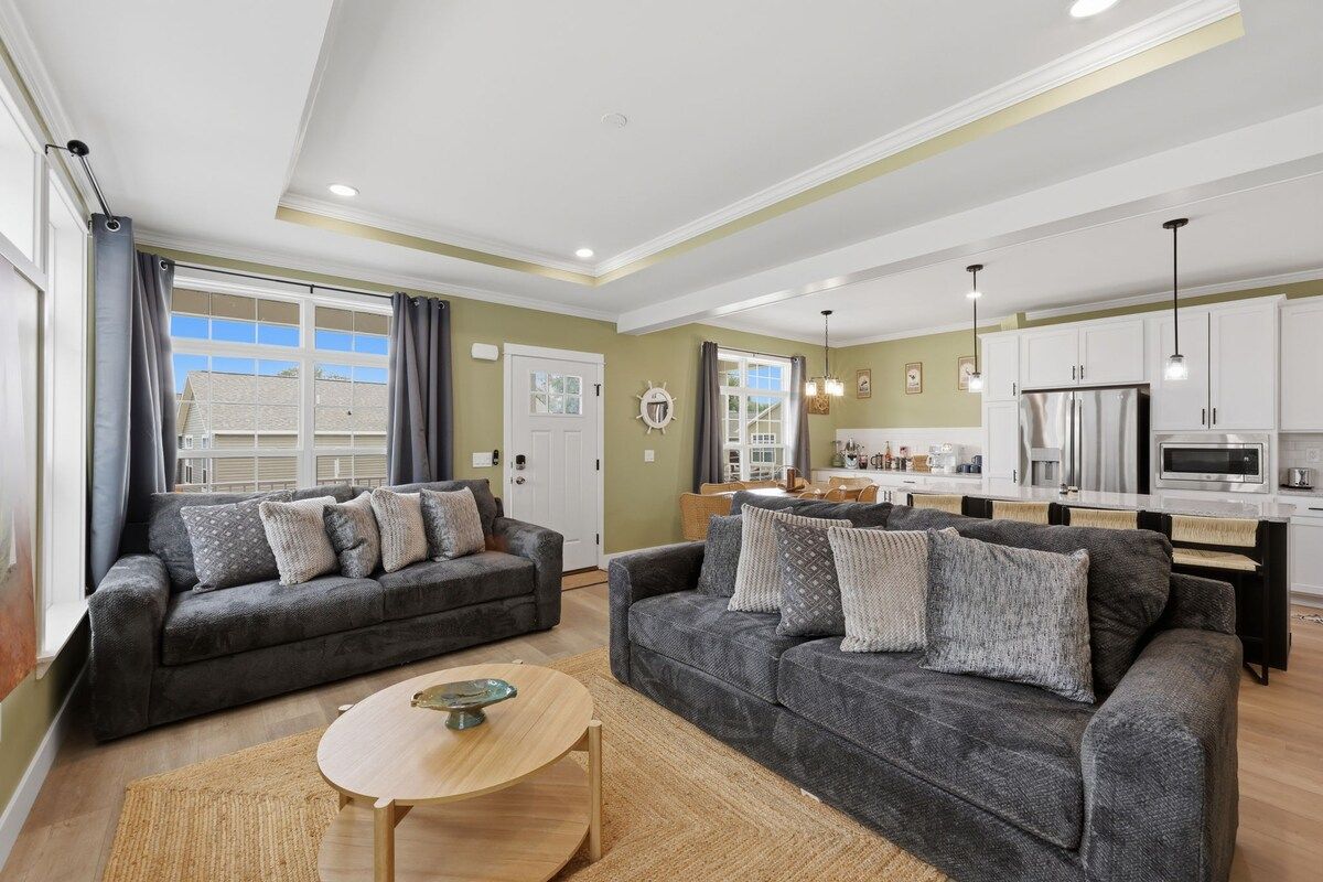 Ein modernes Wohnzimmer mit zwei Sofas, einem Couchtisch und einer Küche im Hintergrund.