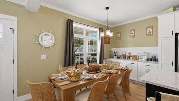 A dining area with a long table set for a meal, surrounded by wicker chairs.