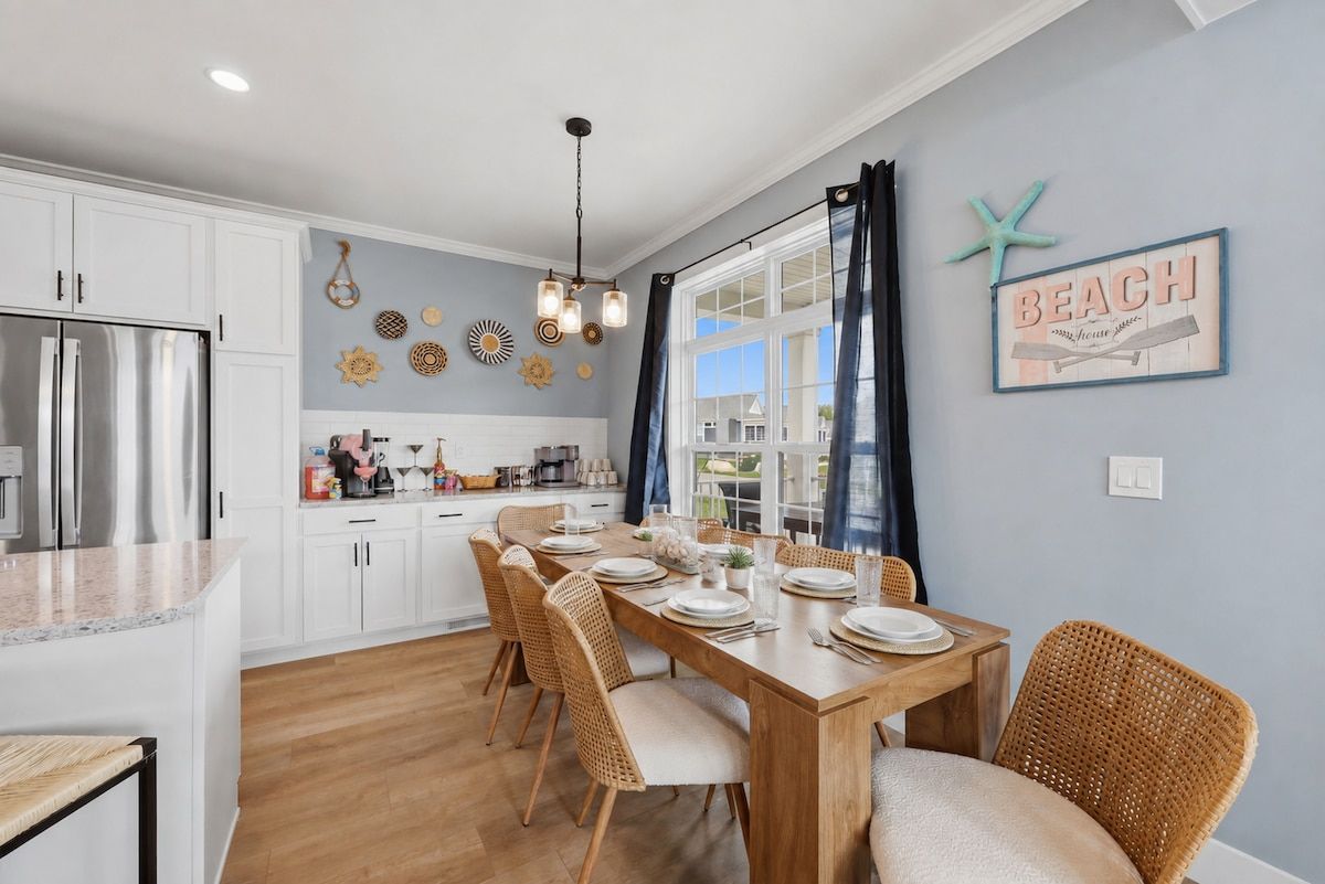 A dining area with a wooden table set for six, surrounded by wicker chairs.