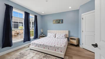 A bedroom with a bed, a nightstand, a door, and a window with curtains.