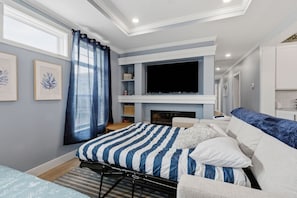 A modern bedroom with a bed, a television, and a fireplace. - Baypoint Duo-Arcade, Beach, Pool, Billiards, Bar (Lakeside Marblehead)