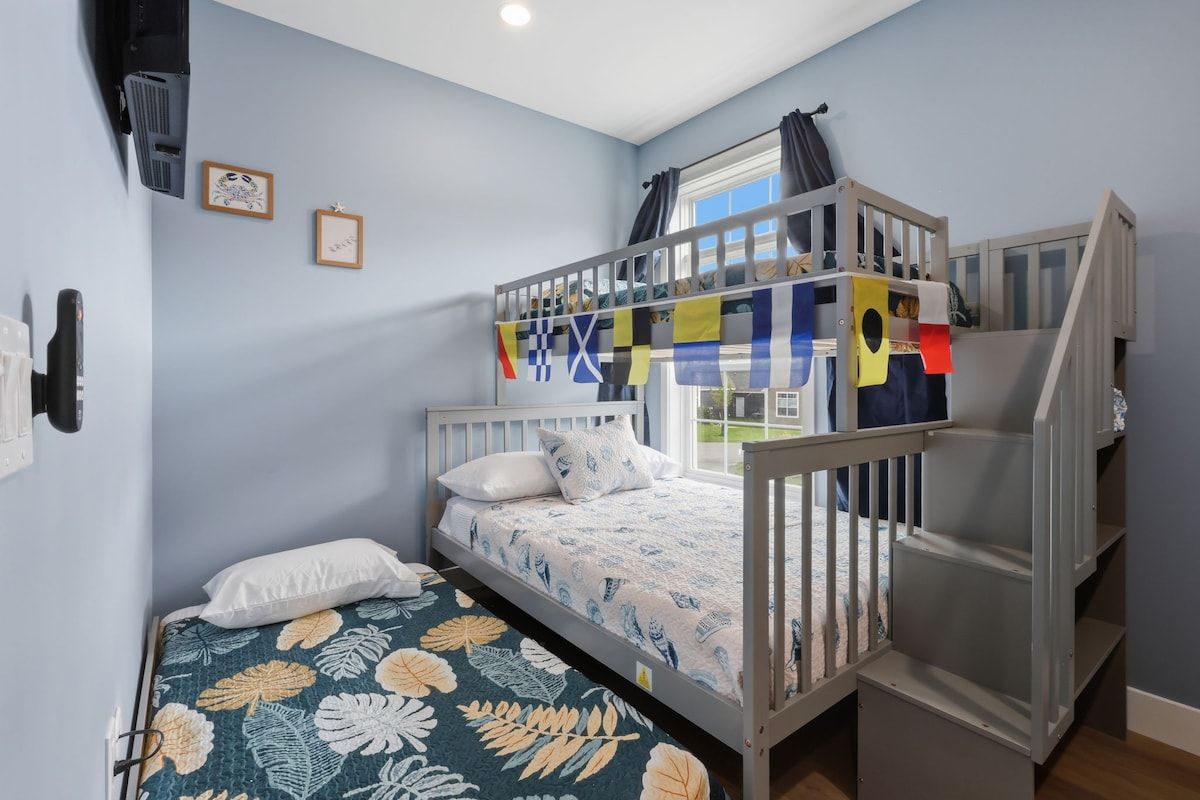 A bedroom with a bunk bed, a single bed, and a window with curtains.