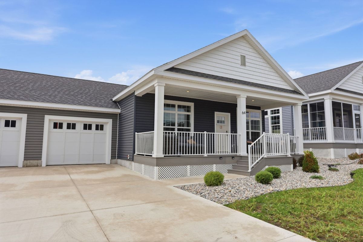 A two-story house with a covered porch, a garage, and a well-maintained lawn.