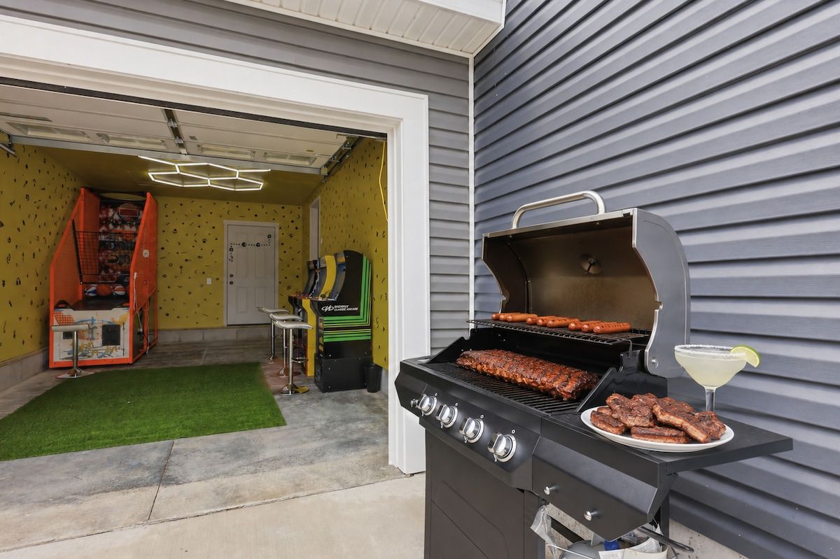 A barbecue grill with meat, a margarita glass, and a green artificial turf in a backyard.