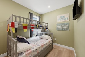 Une chambre avec des lits superposés, une fenêtre avec des rideaux et des affiches motivantes au mur.