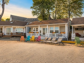 Une rangée de maisons de plage avec un patio en gravier et des fauteuils Adirondack aux couleurs vives.