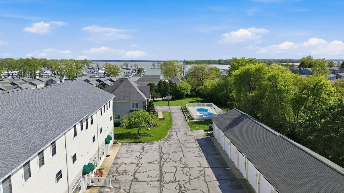 A residential area with multiple houses, a swimming pool, and a view of a body of water.