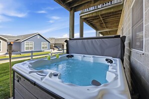 Een jacuzzi met een houten terras en uitzicht op omliggende huizen.