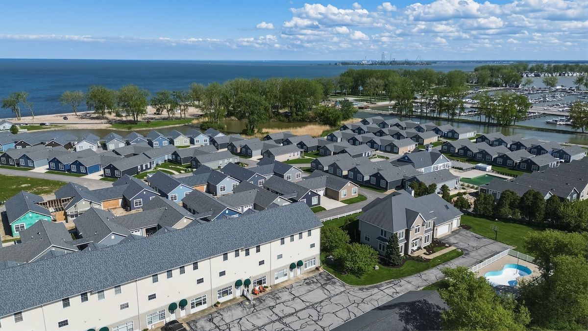 A residential area with multiple houses, a swimming pool, and a marina in the background.