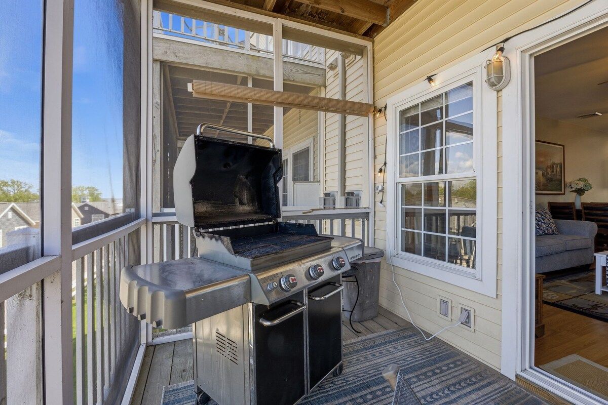 An outdoor grill area with a chimney, a window, and a door leading to an interior space with a sofa.