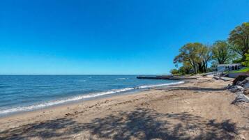 Une plage avec un ciel dégagé, une mer calme et un rivage rocheux.