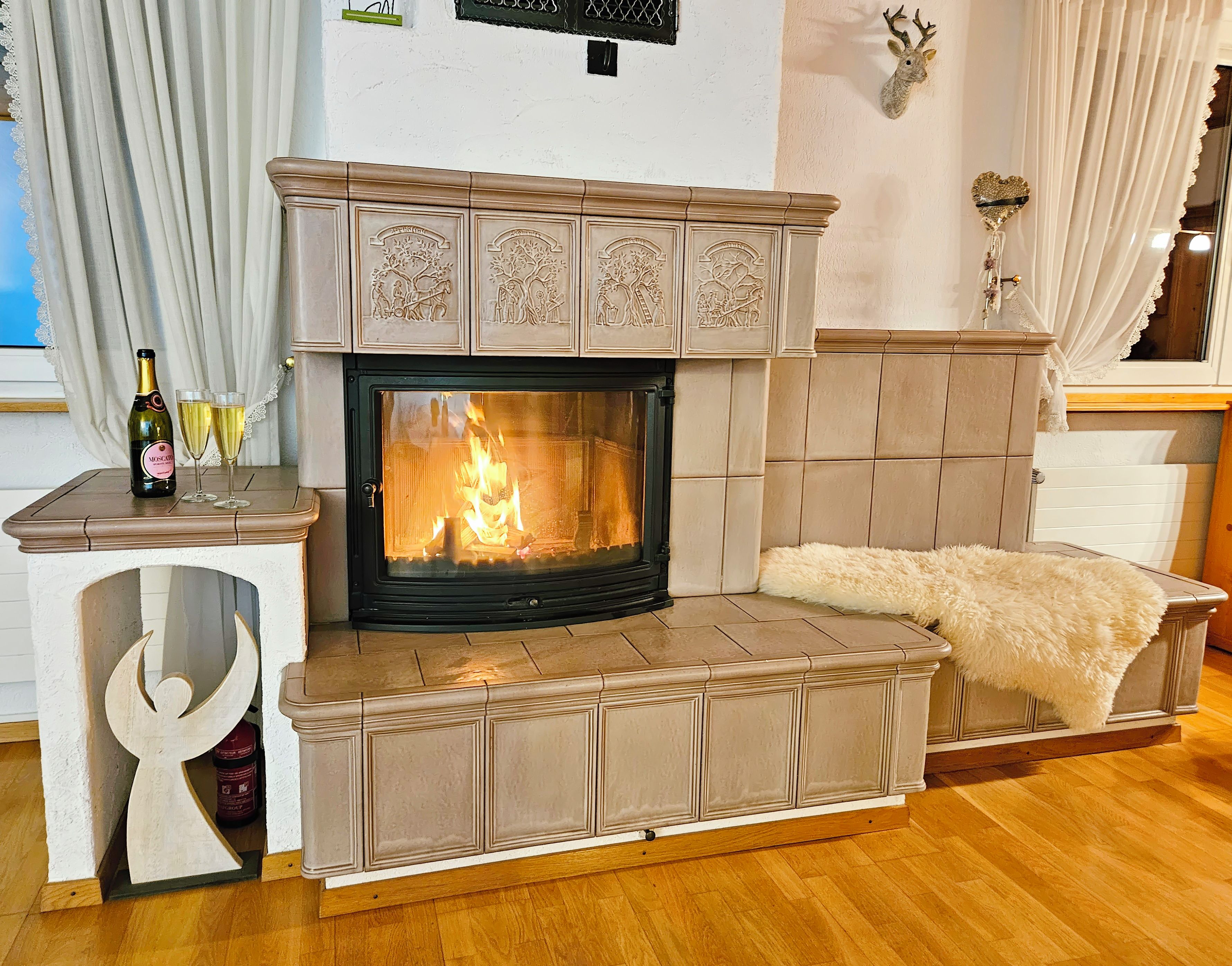 Una chimenea con repisa, una mesa con una botella y vasos, y un adorno de pared.