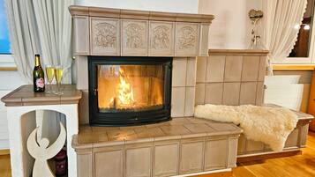 Una chimenea con repisa, una mesa con una botella y vasos, y un adorno de pared.