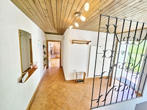 A hallway with a wooden ceiling, a metal gate, and a view into a room with a tiled floor. - Panorama House with a View of Three Countries (Sevelen)