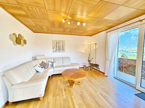 A modern living room with a wooden ceiling, a white sofa, a wooden coffee table, and a deer sculpture. - Panorama House with a View of Three Countries (Sevelen)
