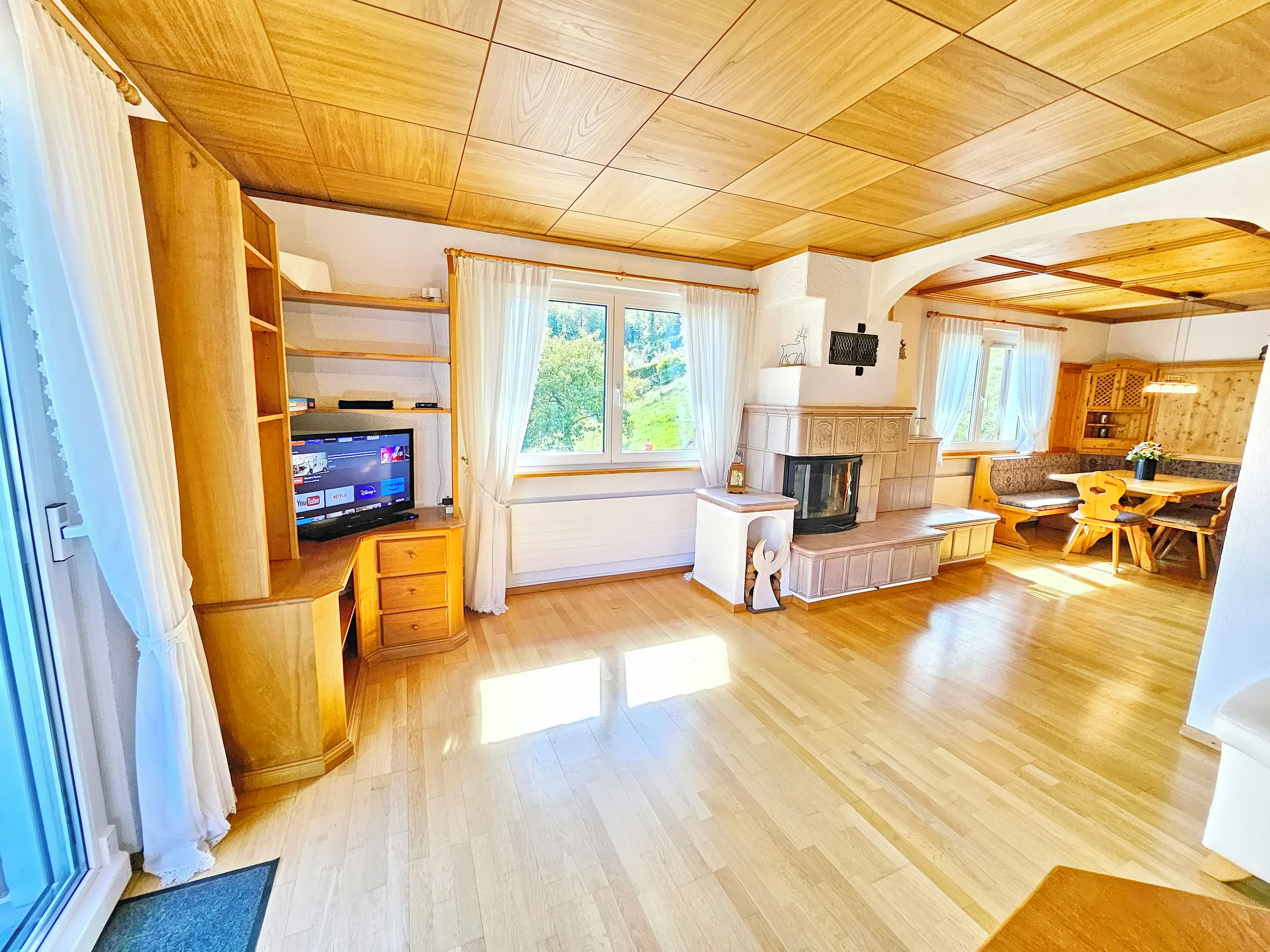 Ein geräumiger Wohnbereich mit Holzboden, einem Kamin, einem Fernseher und einem Essbereich mit Holztisch und -stühlen.