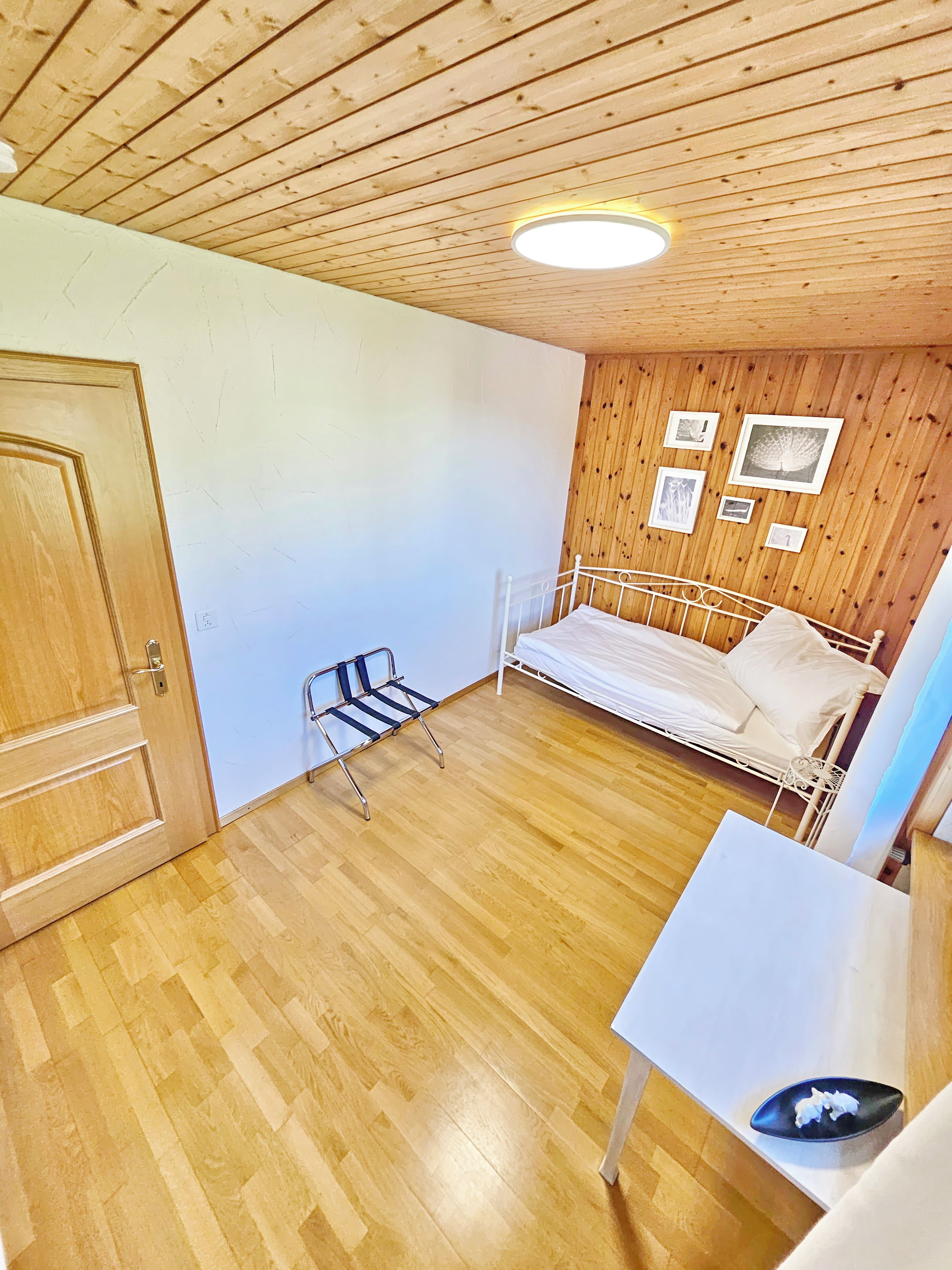 Une pièce aux murs en bois, avec un lit, un banc et une petite table.