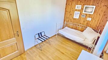 Une pièce aux murs en bois, avec un lit, un banc et une petite table.