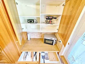 A compact kitchen with a microwave, toaster, and a wooden cutting board drawer. - Panorama House with a View of Three Countries (Sevelen)