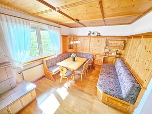 A cabin interior with a wooden dining table, benches, and a kitchen area. - Panorama House with a View of Three Countries (Sevelen)