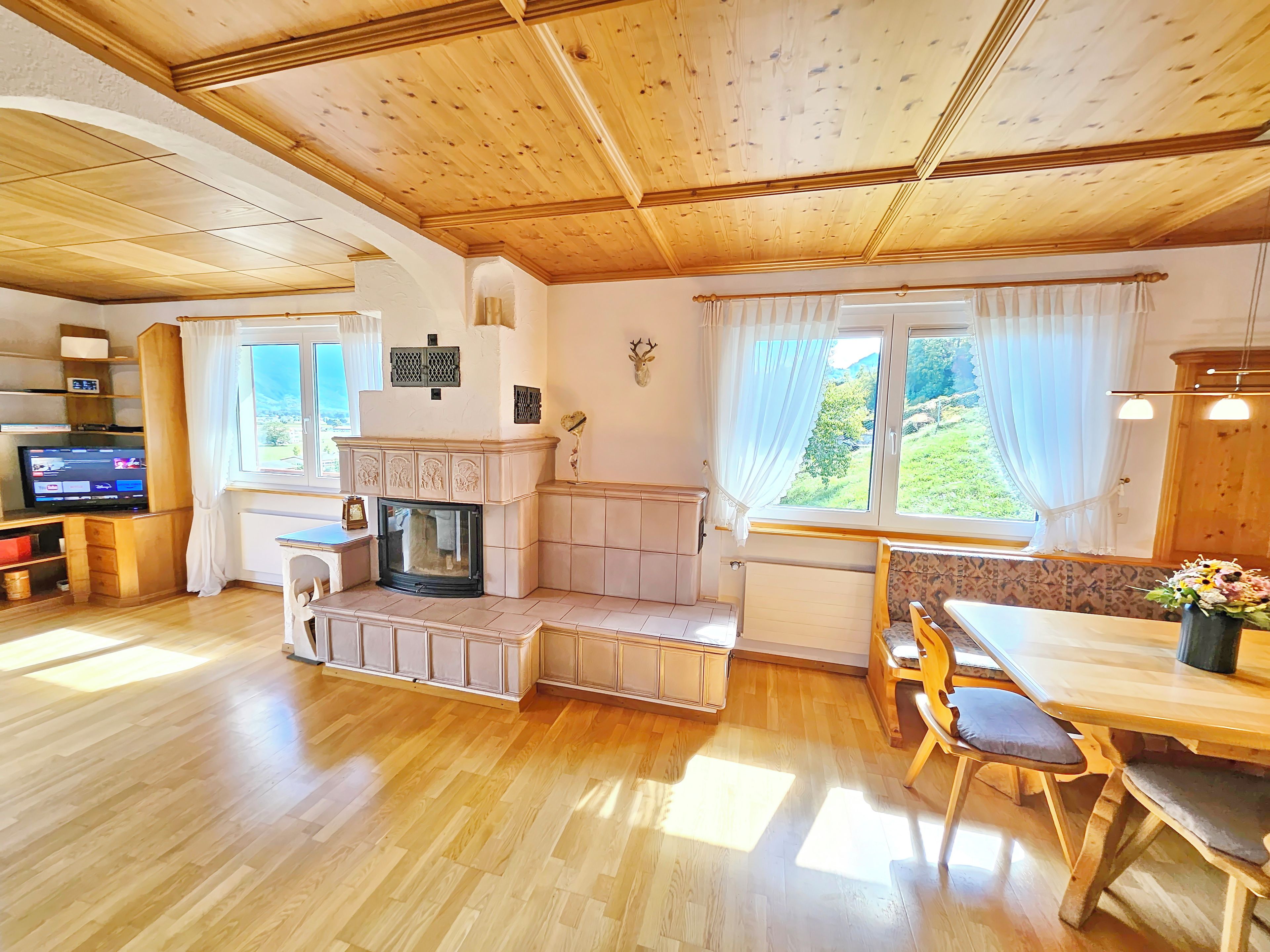 Una habitación acogedora con chimenea, techo de madera y una zona de comedor con mesa y sillas.