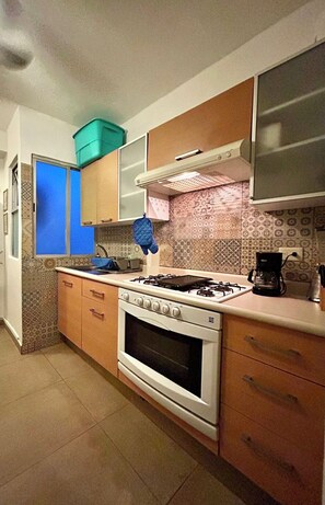 Une cuisine équipée d’une cuisinière à gaz, d’un four et d’une machine à café.