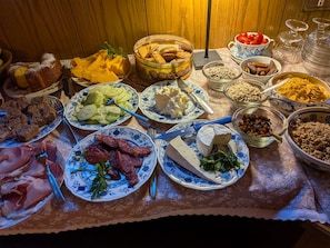 Uma mesa com diversos alimentos, incluindo queijo, embutidos e vegetais.