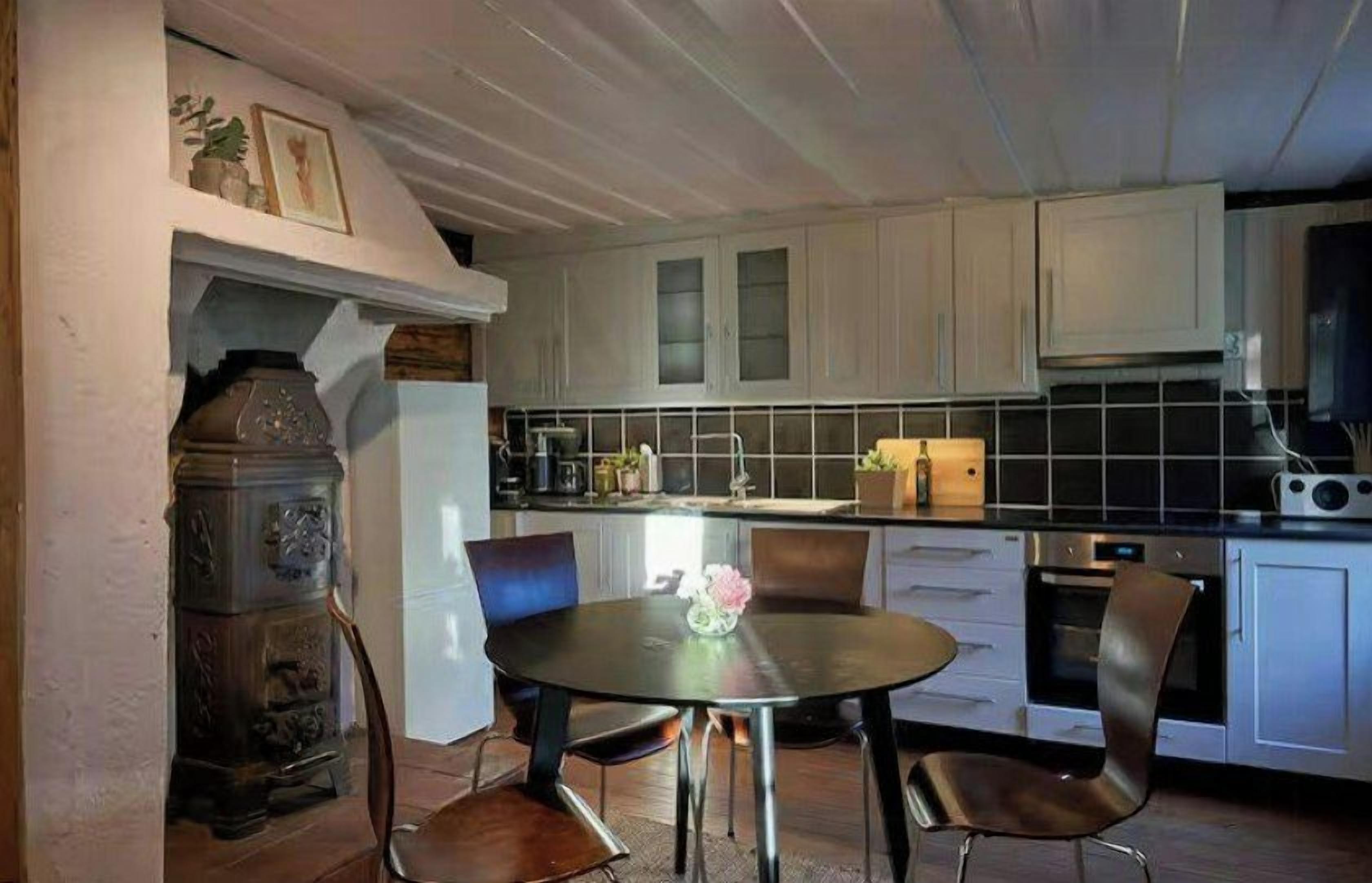 Une cuisine avec une table de salle à manger ronde, des chaises et un fourneau.
