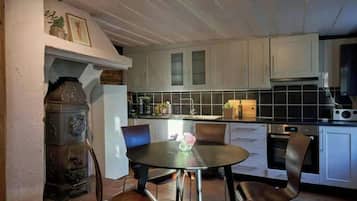Une cuisine avec une table de salle à manger ronde, des chaises et un fourneau.