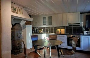 Una cocina con una mesa redonda, sillas y una estufa.
