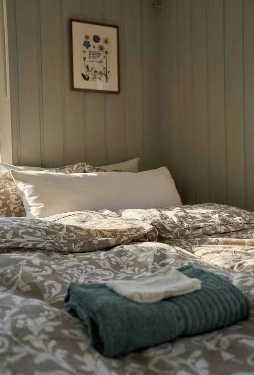 Un lit bien fait, avec une literie à motifs, un oreiller et une couverture pliée.