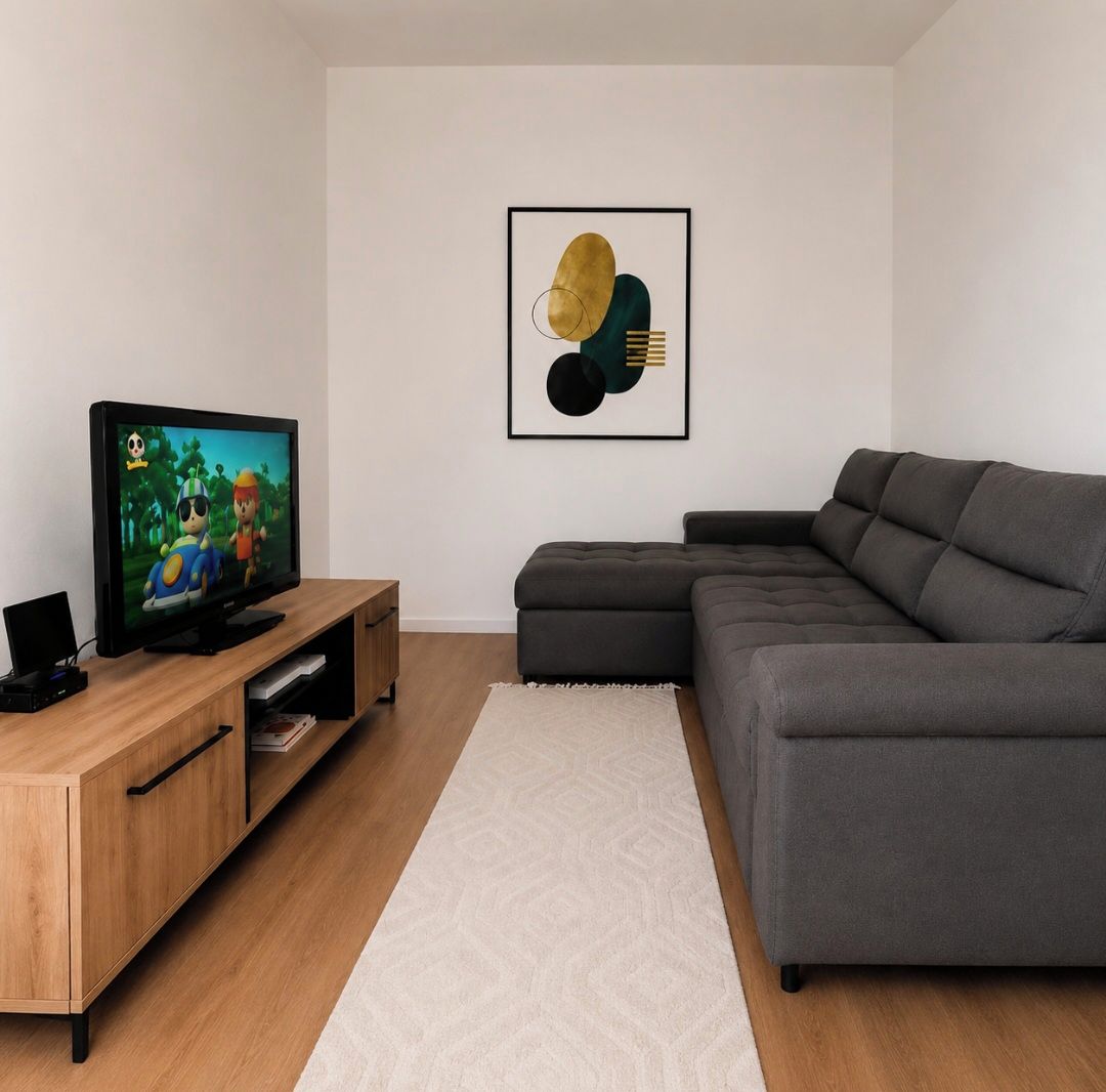 A modern living room with a flat-screen TV, a grey sectional sofa, a wooden entertainment unit, and a geometric abstract painting on the wall.